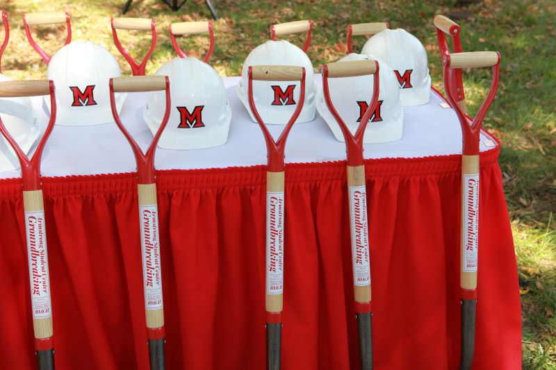 5 shovels and 5 construction helmets on a table 