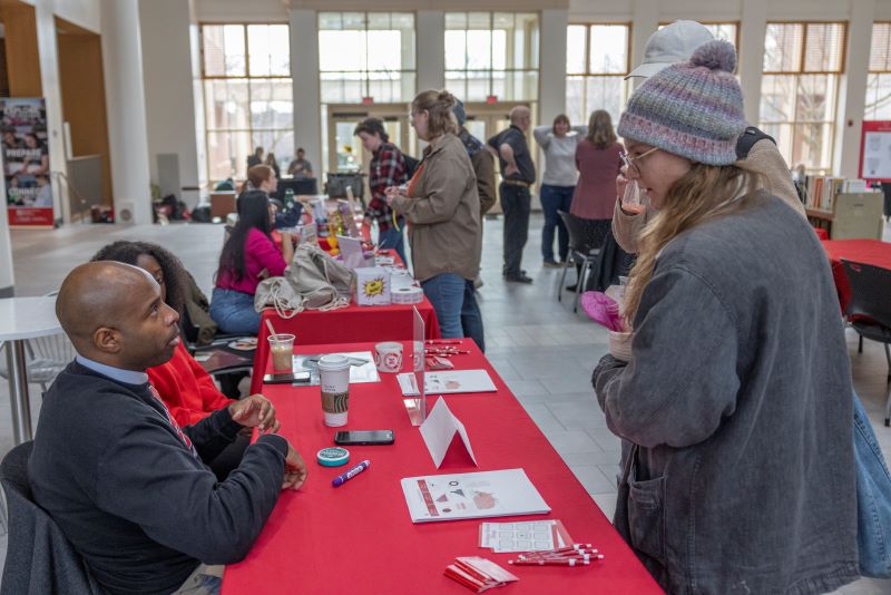 two people sitting at table talking to one women standing 