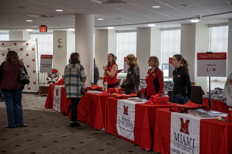 people standing behind a line of tables talking to those entering event
