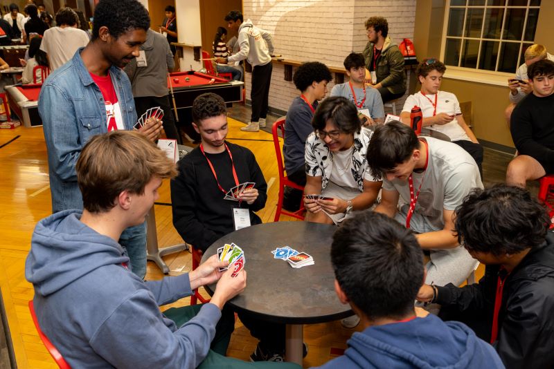 students sitting at round tables playing cards 