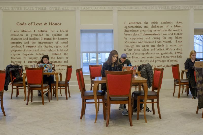 students sitting at tables on a stage studying