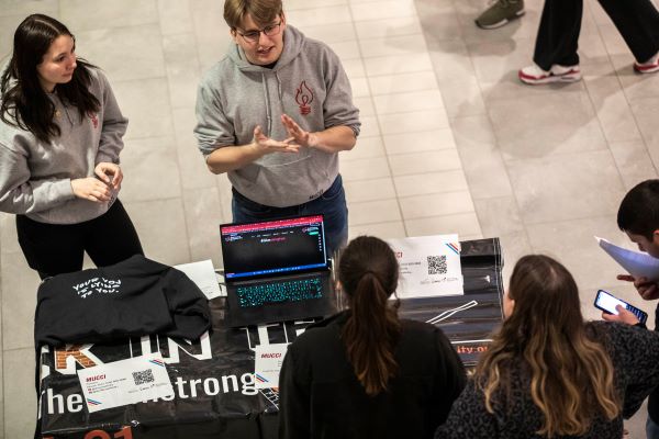 Students stand around table talking