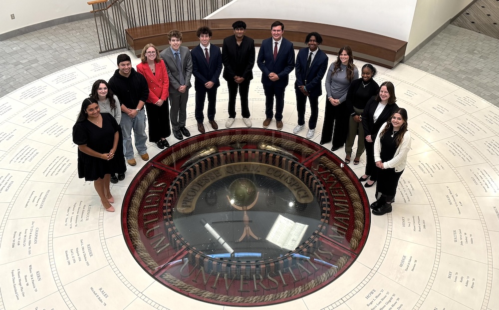13 members of the Armstrong Student Center Board, posing around the indoor seal in the Armstrong rotunda.