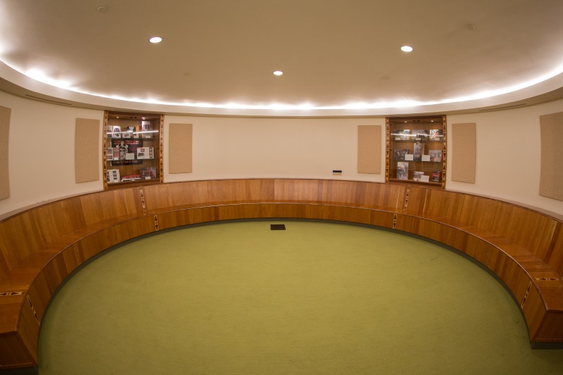 Circular room with benches lining the walls, built in shelves displaying Myaamia artifacts.
