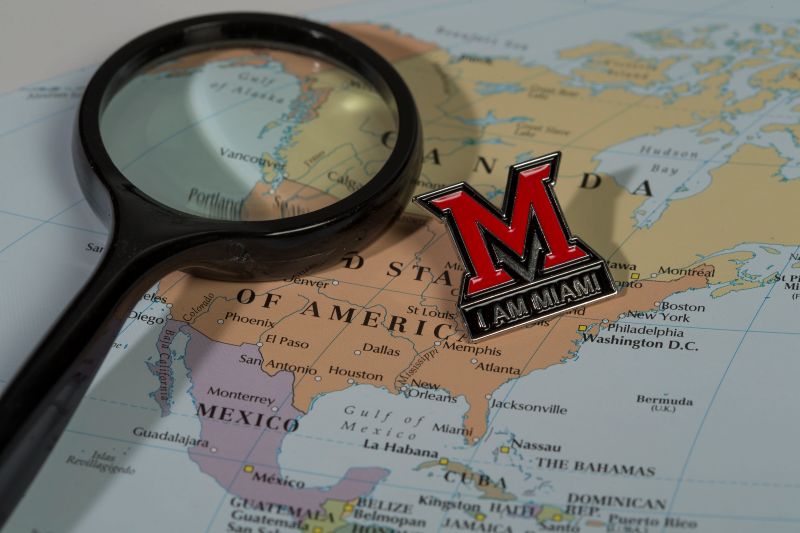 A magnifying glass and a Miami pin sit on top of a map.
