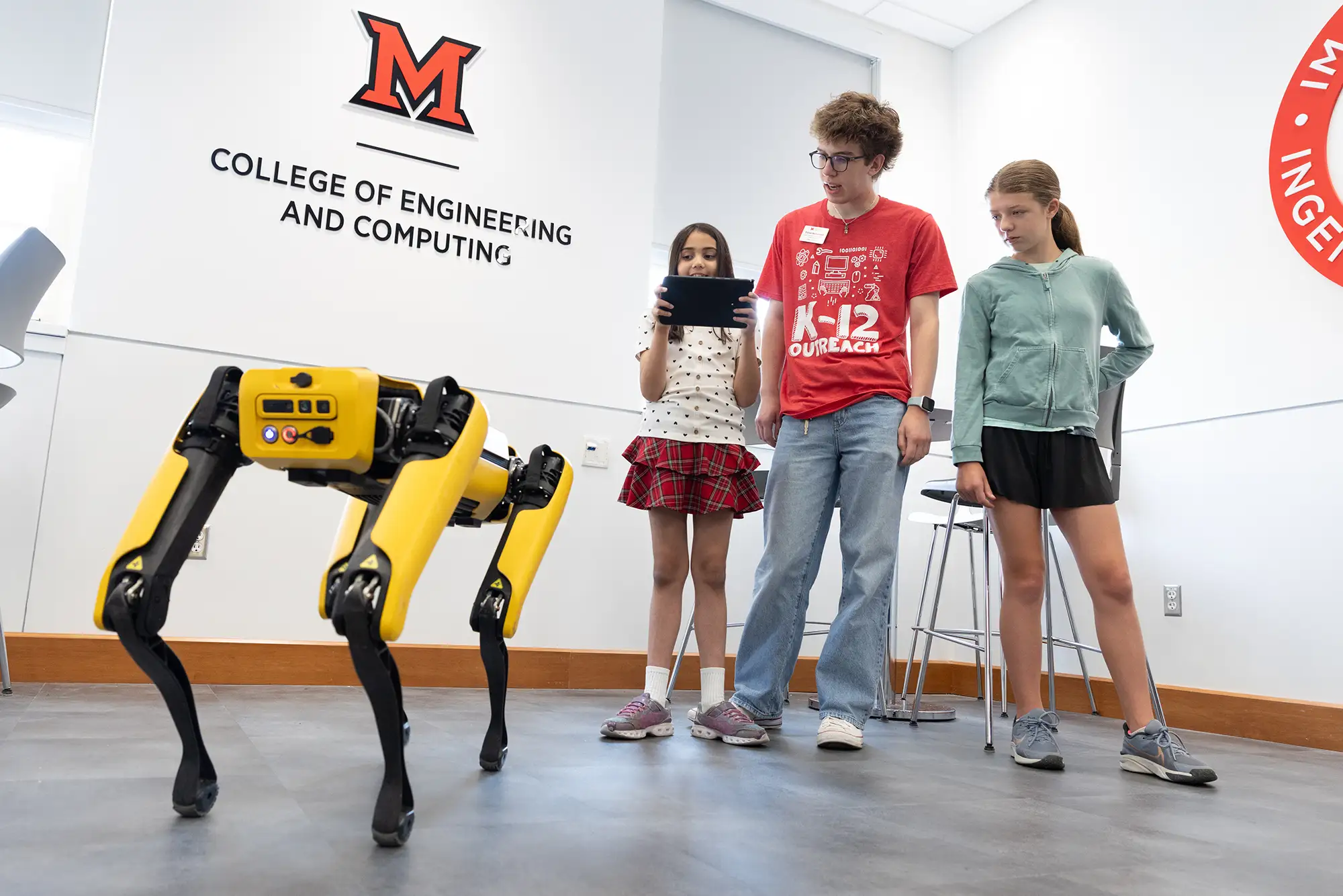 Miami students and children working with Miami’s robot dog