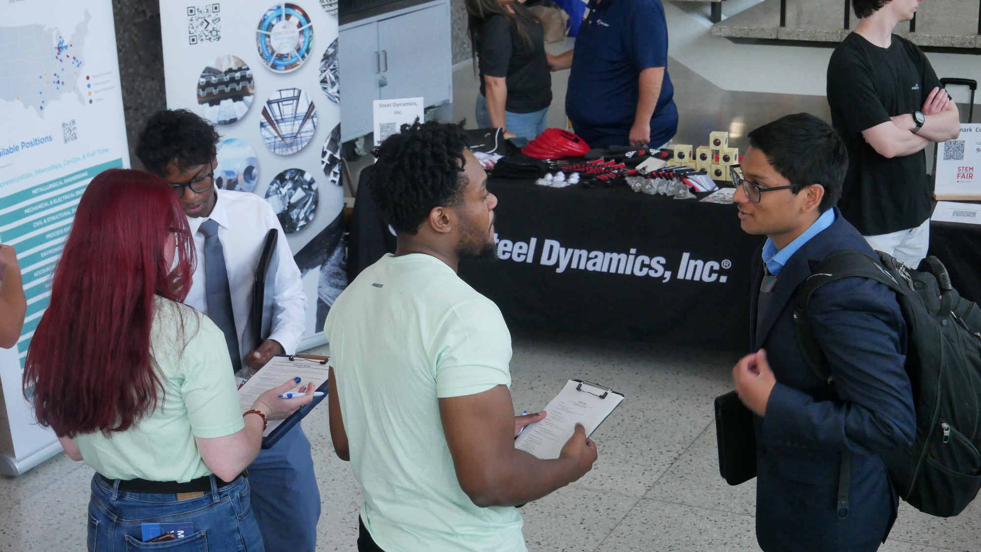 Two students speak with two employers at a career fair.