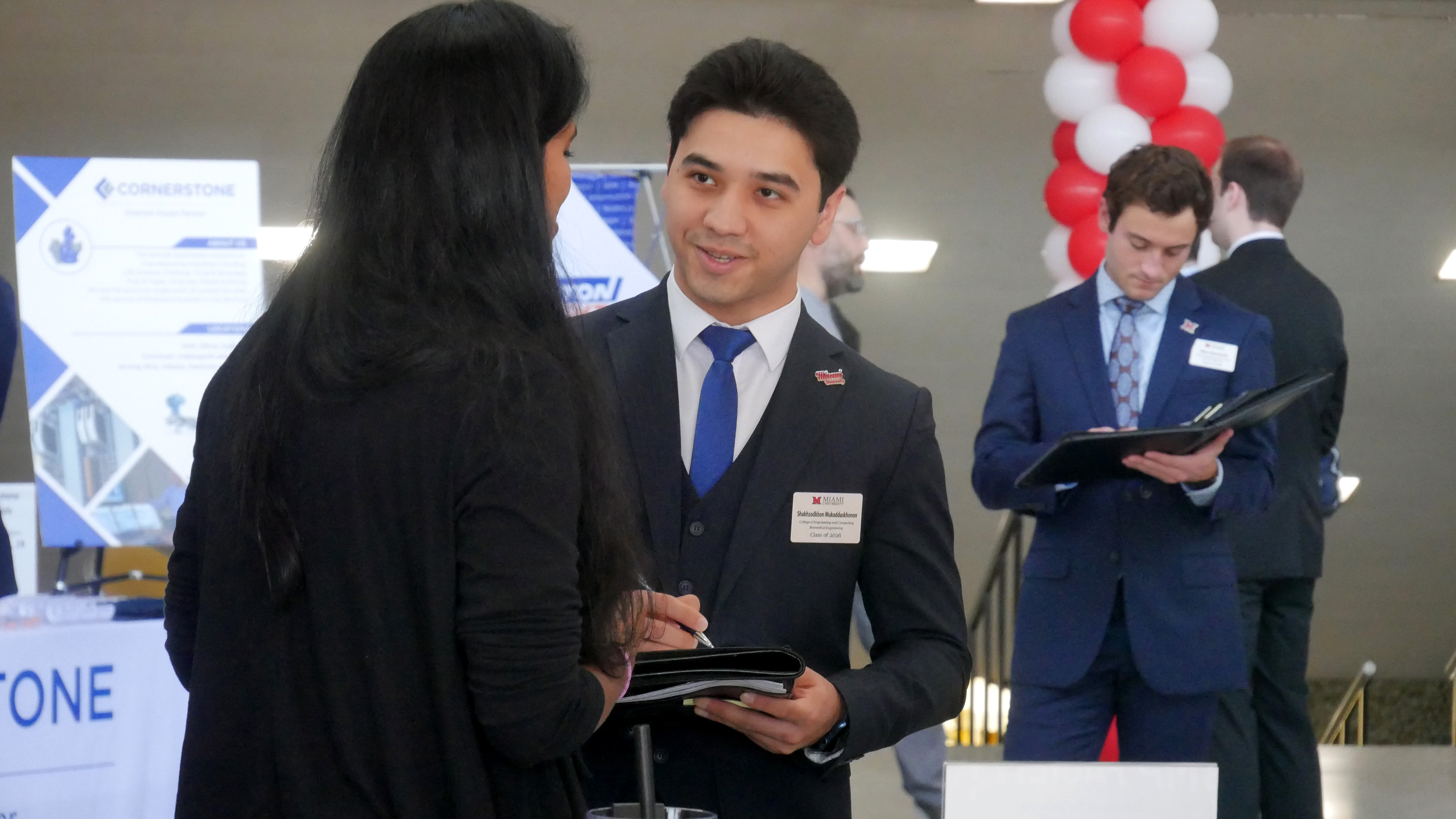 A student smiles while speaking with an employer at a career fair.