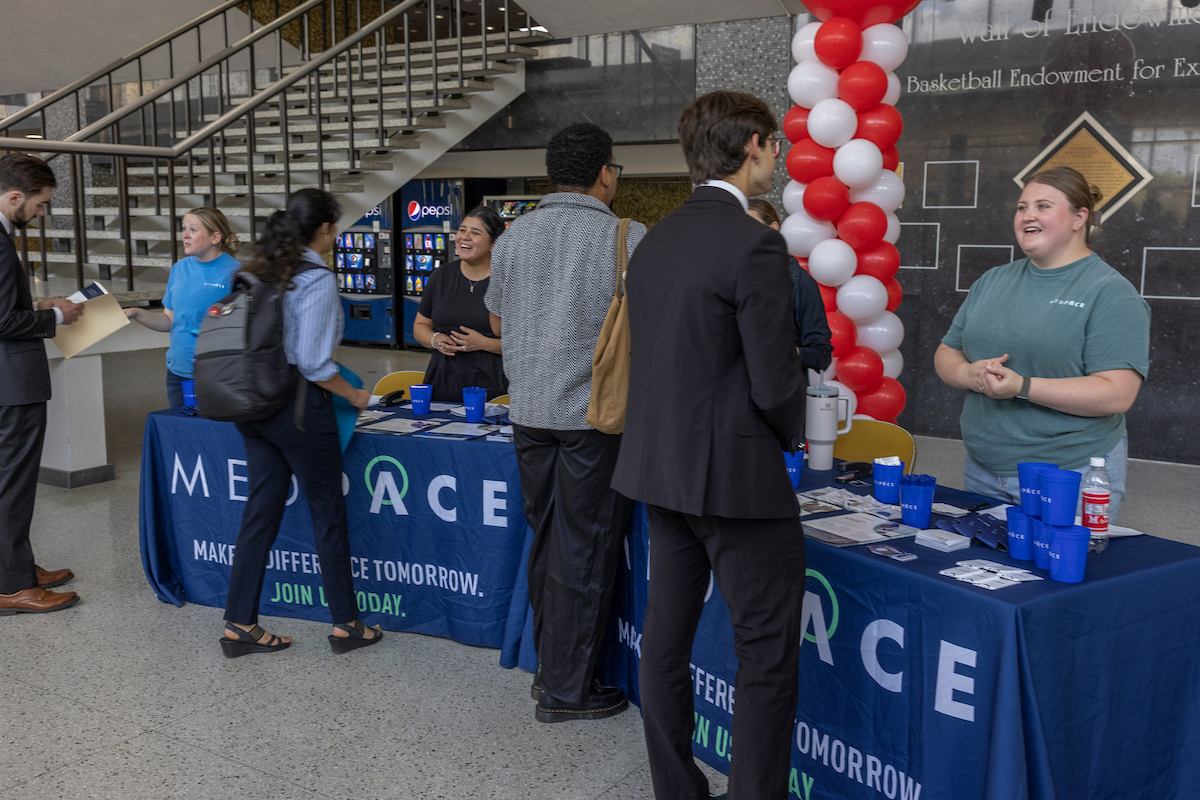 Three Medpace representatives speak with students at a career fair.