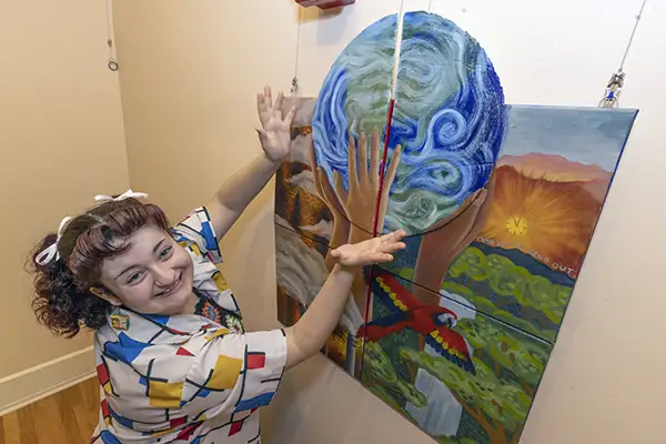 Student using hands as if to hold up a painting of the world