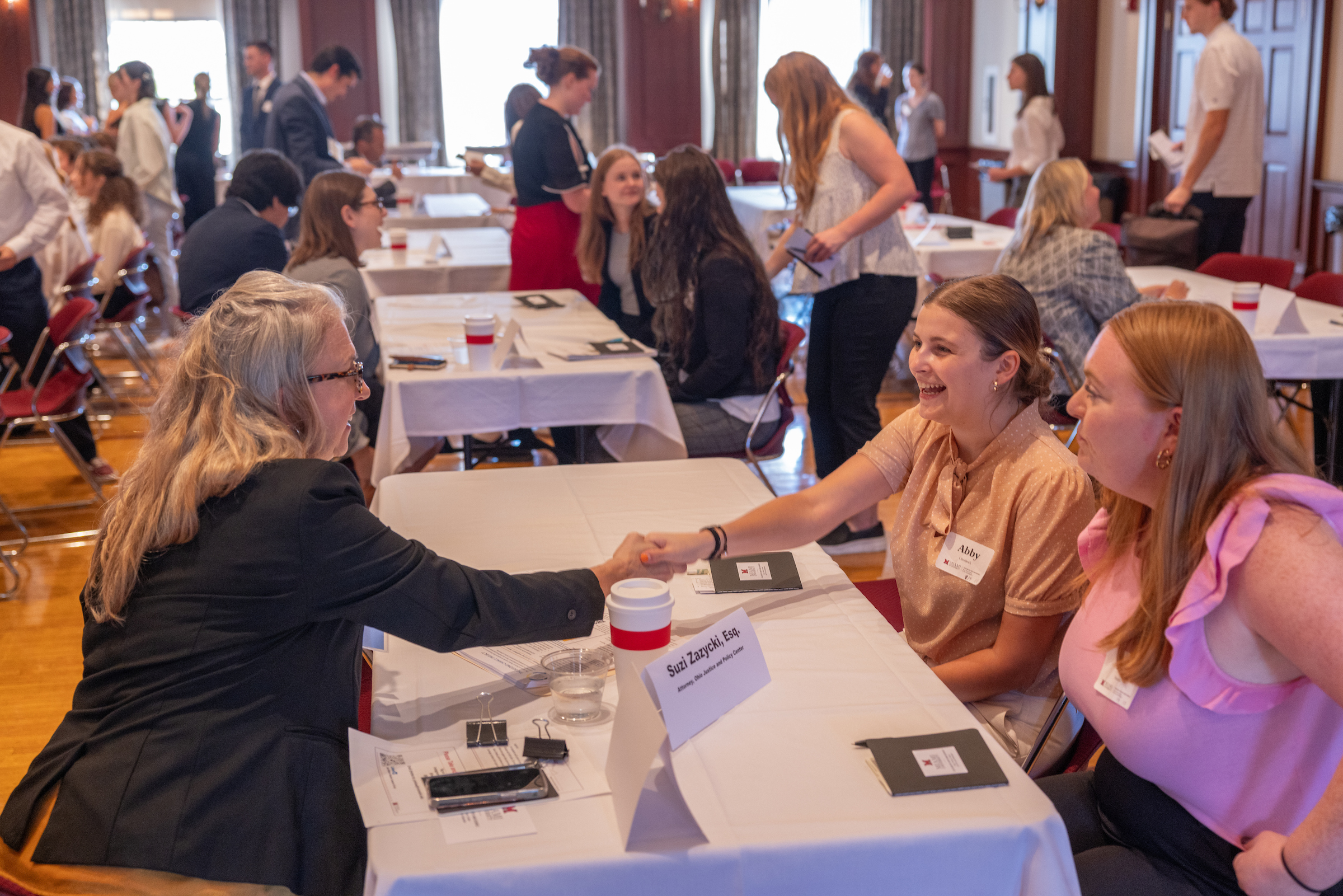 A student shakes hands with a lawyer at a networking event with alumni.