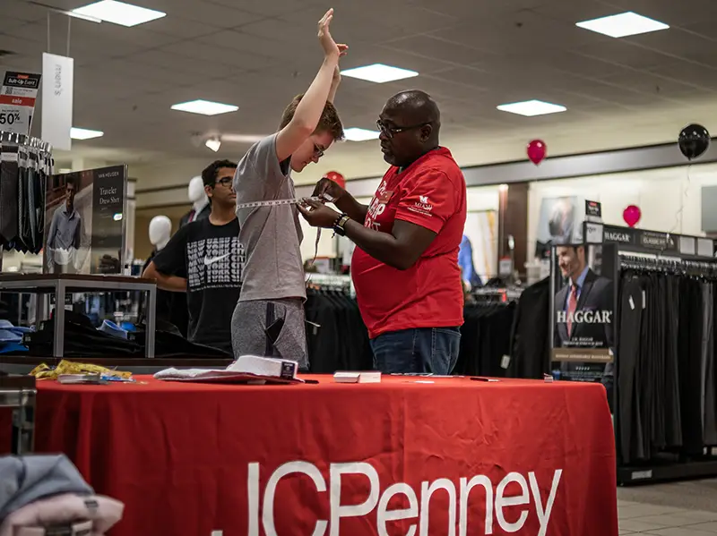 JCPenney employee measures a Miami student to help him choose a suit
