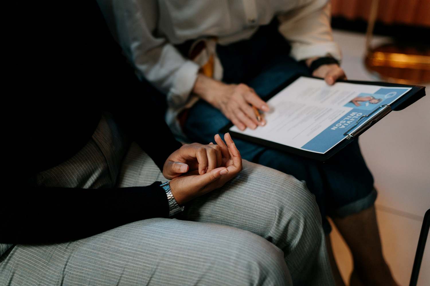 A resume is reviewed by two seated people.