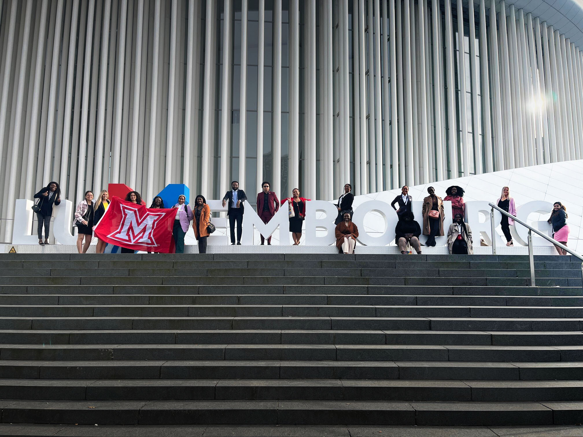 Students pose in front of a sign reading Luxembourg during a Career Academy experience.