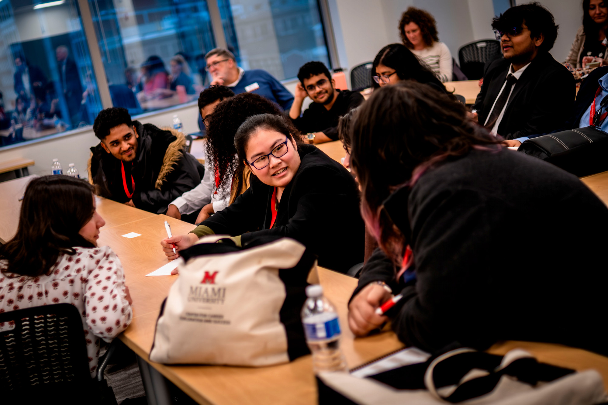 Students sit at conference tables while listening to a presentation at a site visit.