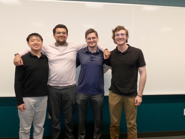 The data dolphins team standing side by side with arms around each other in front of a whiteboard.