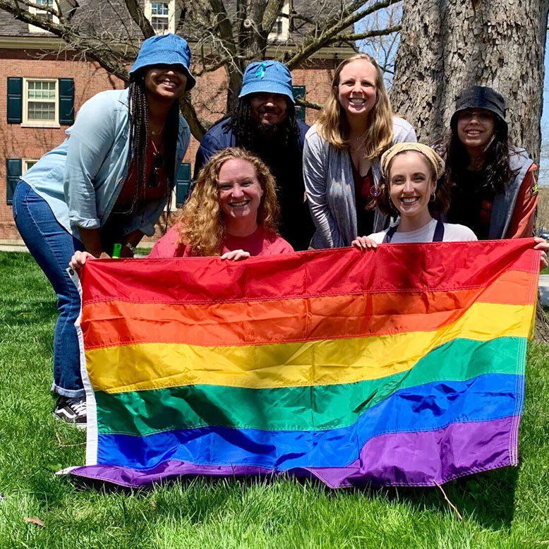Five csdi staff members posing in front of a rainbow pride flag.