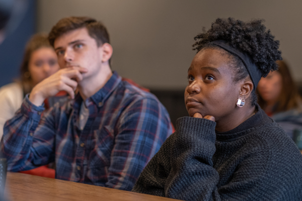 Two students in a classroom, looking up and engaged