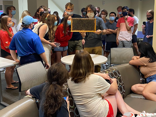Large crowd of students wearing masks in the Hahne Hall lobby, with Rob Abowitz holding up a frame of honey bees.