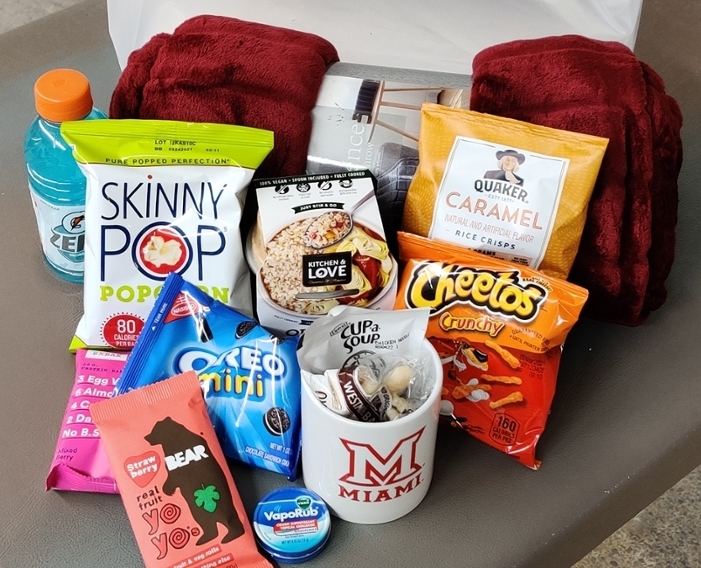 Care package including snacks, a blanket, vapo rub, etc.