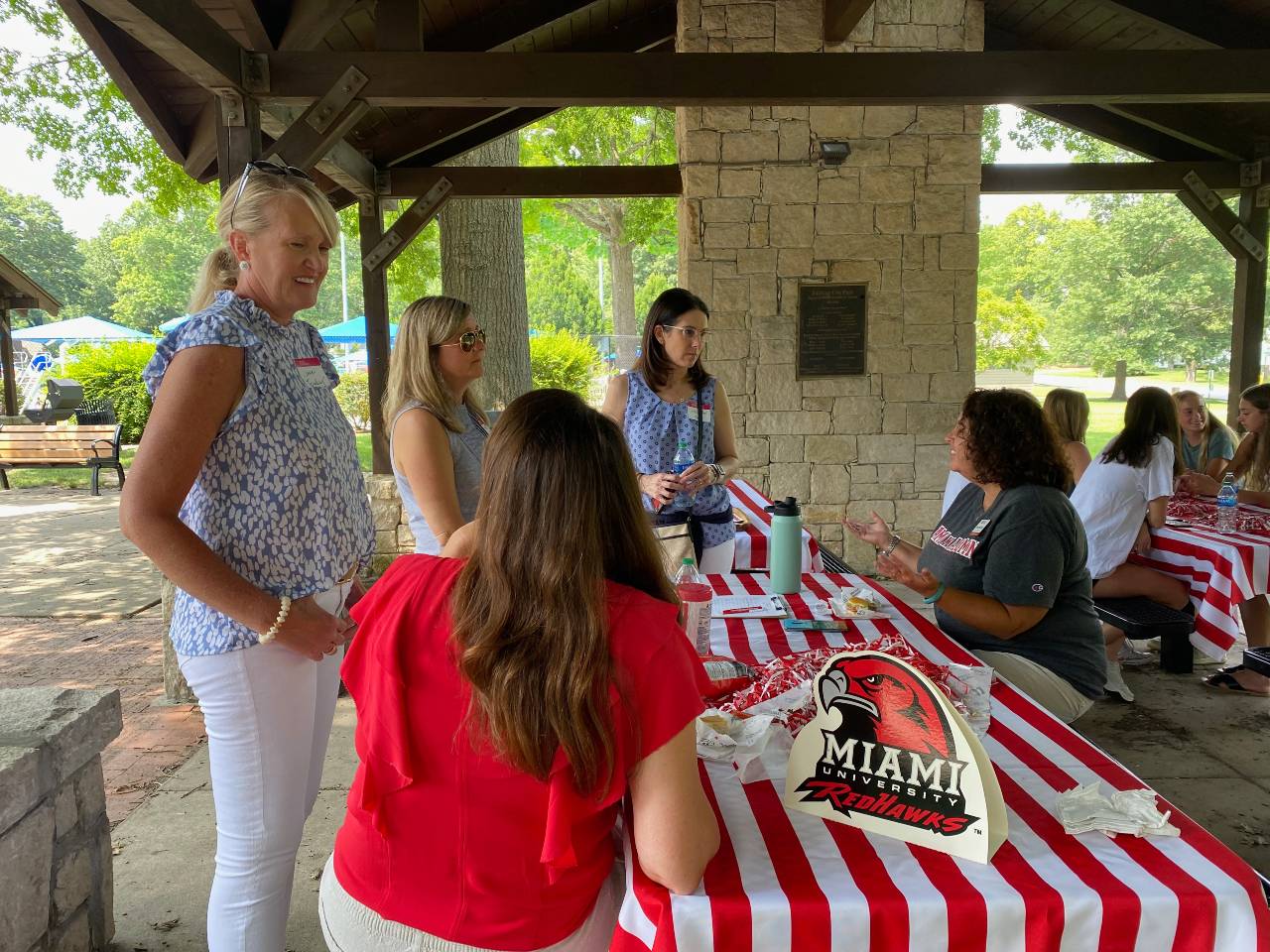 Students and families talking under a picnic shelter