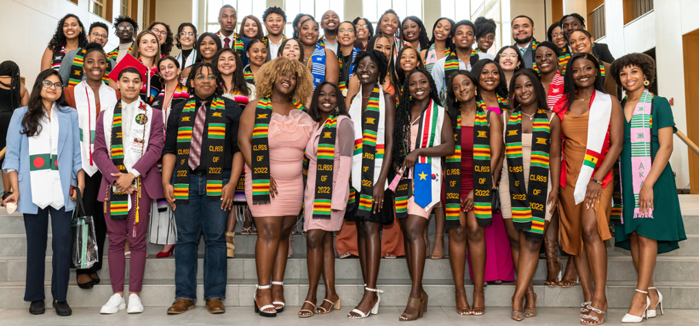 About 50 graduating students in various stoles, smiling at the camera.