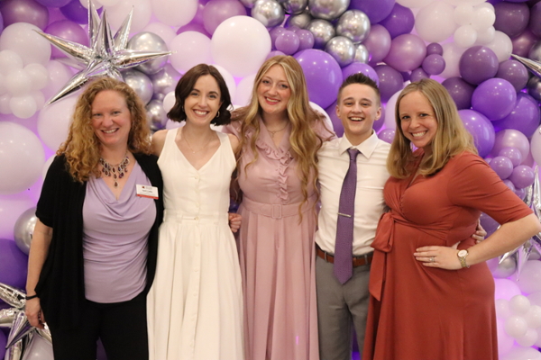 Staff in front of a huge lavender balloon wall.