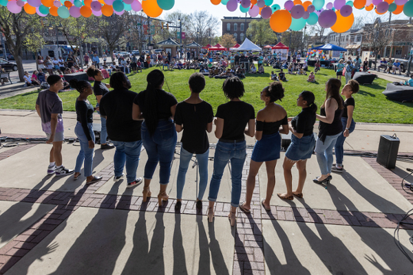 View of Uptown Parks from behind the stage, with about 10 students standing on stage, facing the audience.