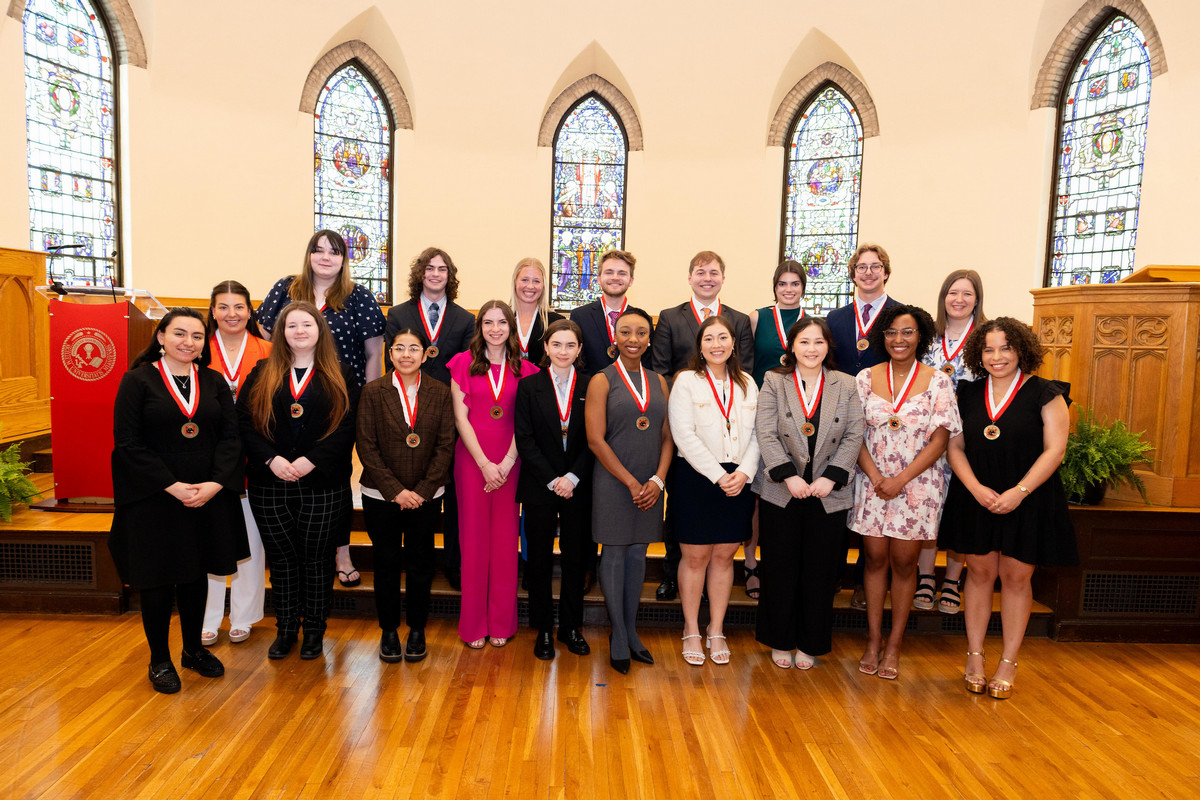 19 students, dressed professionally, posing in two rows at Kumler Chapel.