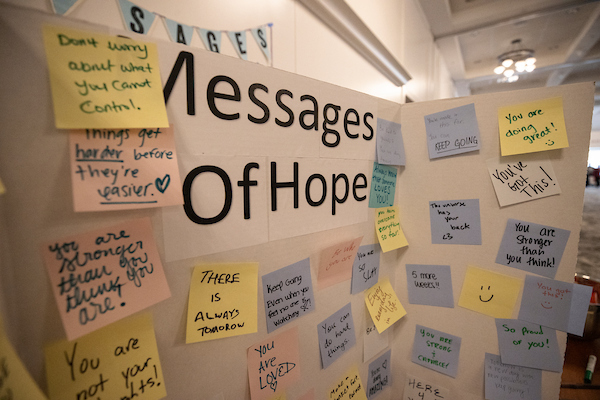 A tri-fold display board with messages of hope written on post it notes and stuck to the board.