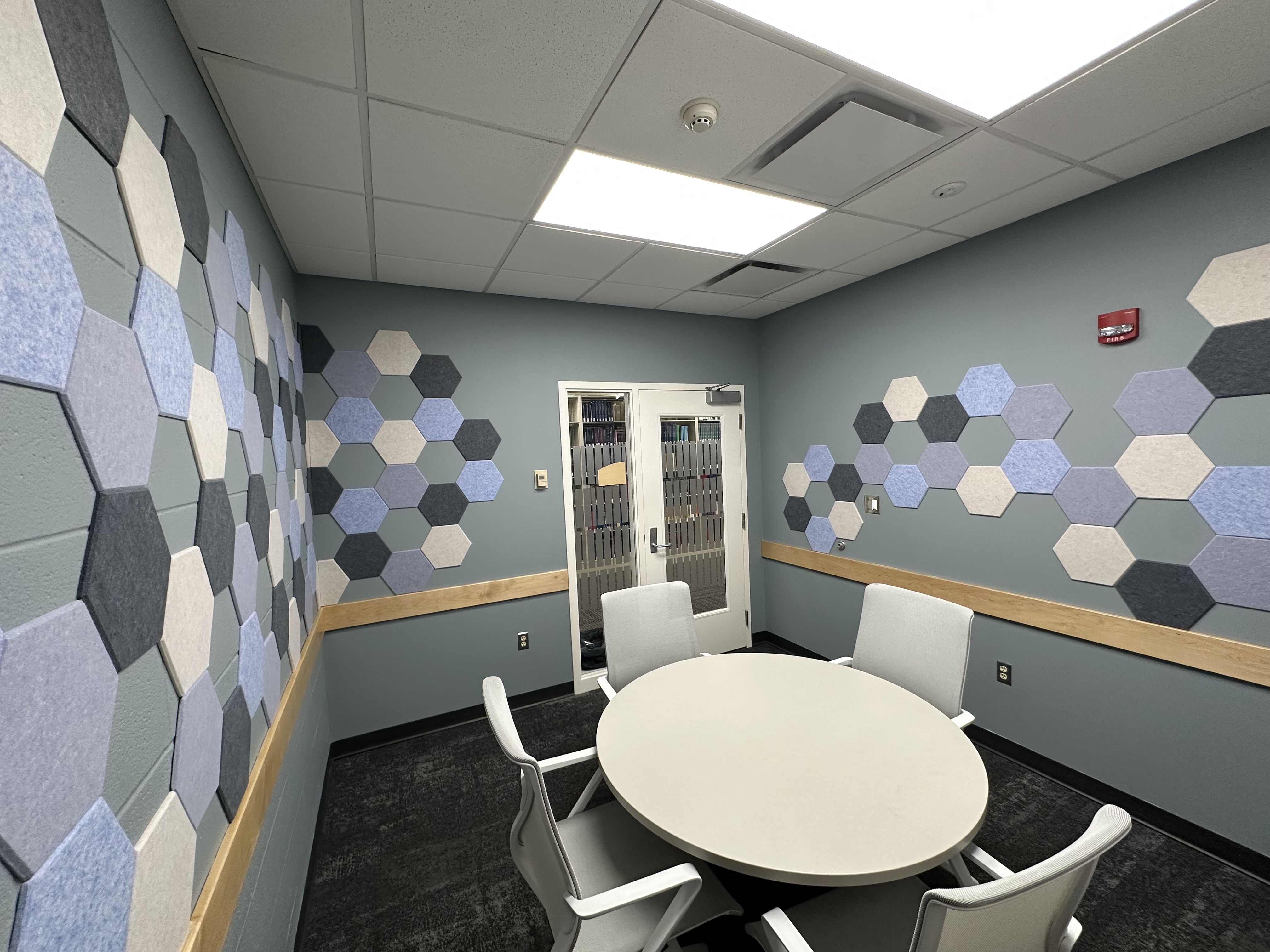 A sensory room featuring a table with chairs in the center, surrounded with acoustic panels on the walls. 
