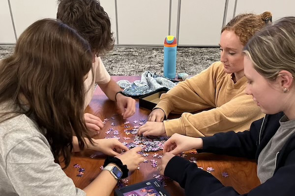four students working on a jigsaw puzzle