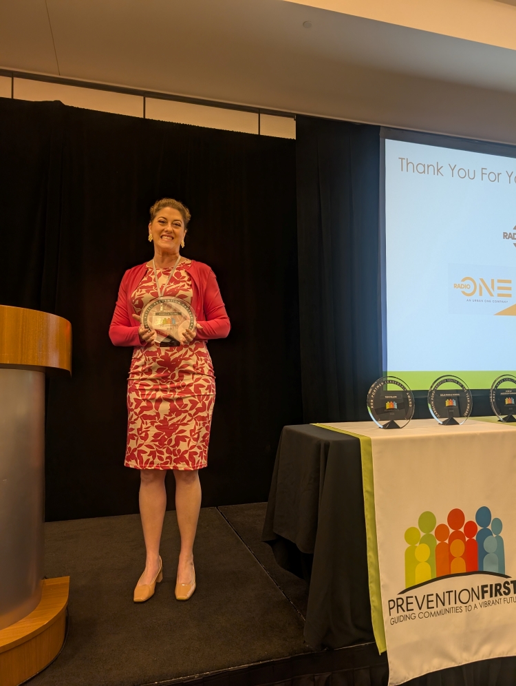 Rebecca Young is on stage at the PreventionFIRST! award ceremony holding her award.