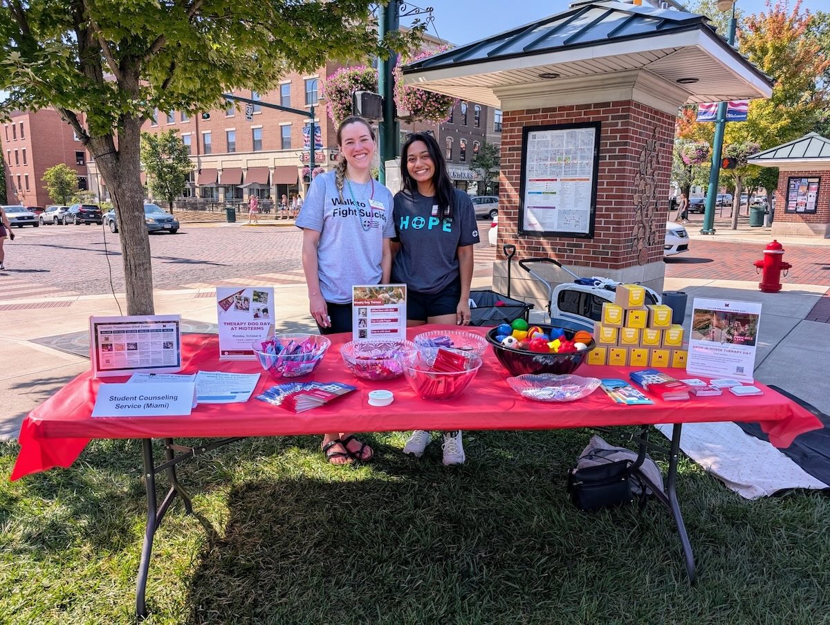Two students working at a table full of suicide prevention material at an event uptown.