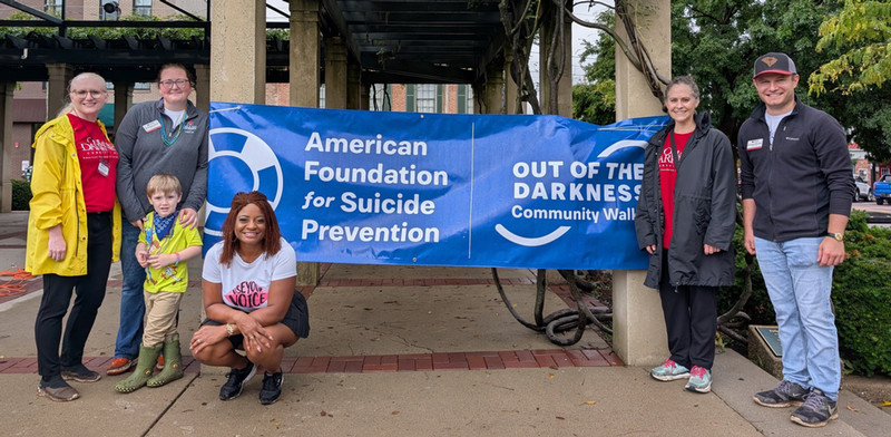 Students and community members gathered by the Suicide Prevention Walk banner in a park