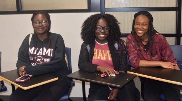 Three women of color sitting at desks in the Rinella Learning Center Seminar Room