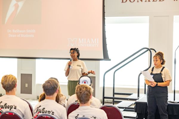 Nyah and Jules stand in front of a large crowd, speaking in the Armstrong Pavilion.