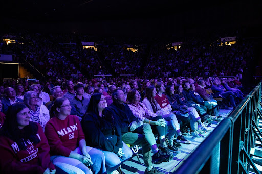 Full audience of in a dark Millett Hall, audience members looking up at a stage. 