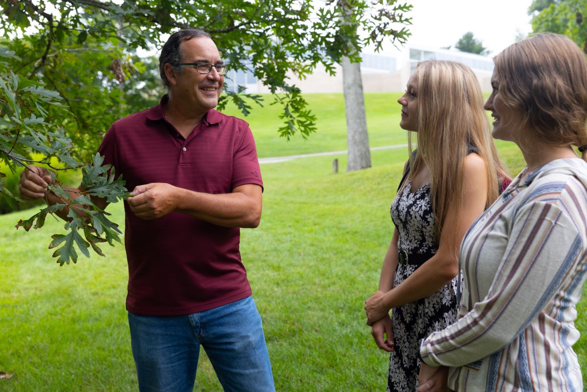 Daryl Baldwin teaching two students about trees on campus