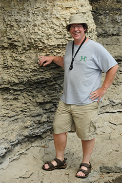 Tim McCoy standing against a rocky wall