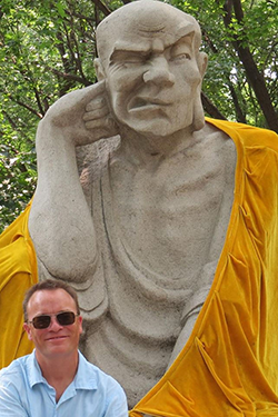 Stephen Warren standing in front of a large monk statue