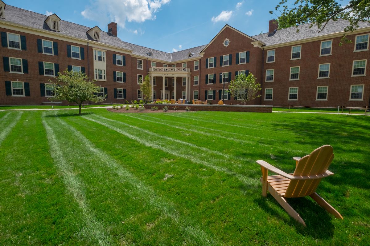 The lawn in front of a red brick residence hall on a sunny day
