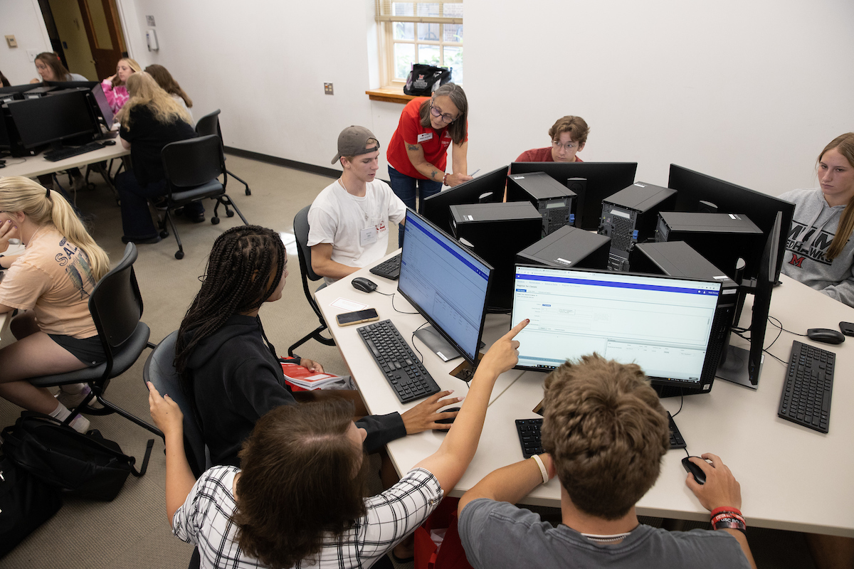 Students work in a computer lab with an advisor.