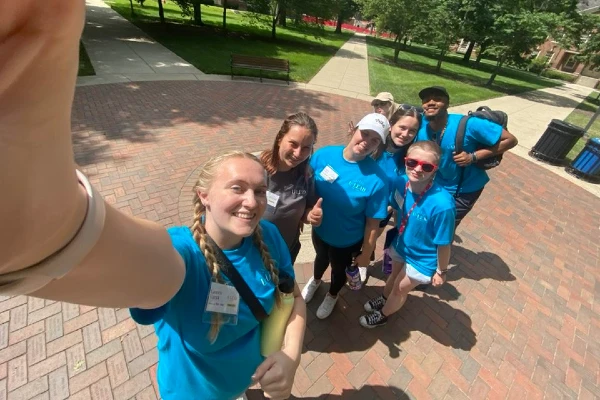 4 students in blue u-lead shirts posing for a selfie