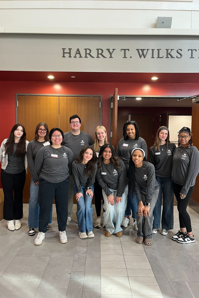 A group of students wearing grey shirts in front of the Wilks Theater.