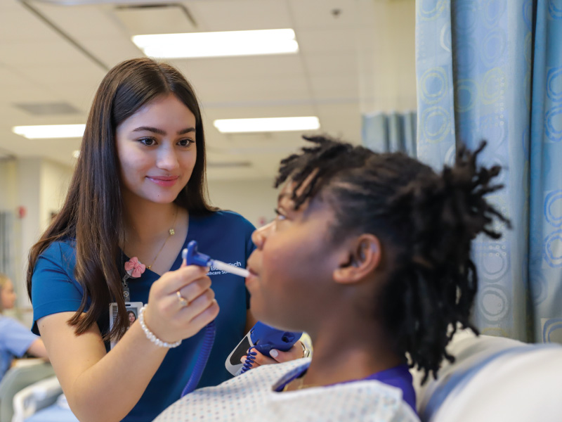 Butler Tech nursing student using a thermometer on a patient in a lab.