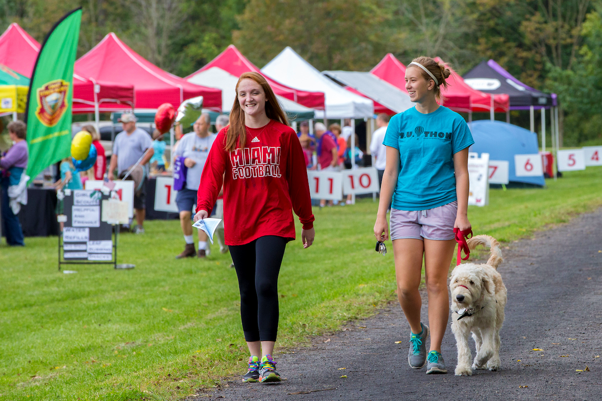 students taking a walk with a dog on campus