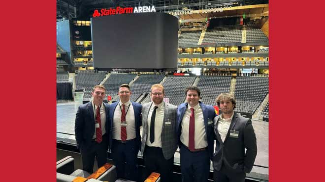5 students dressed in suits inside an arena