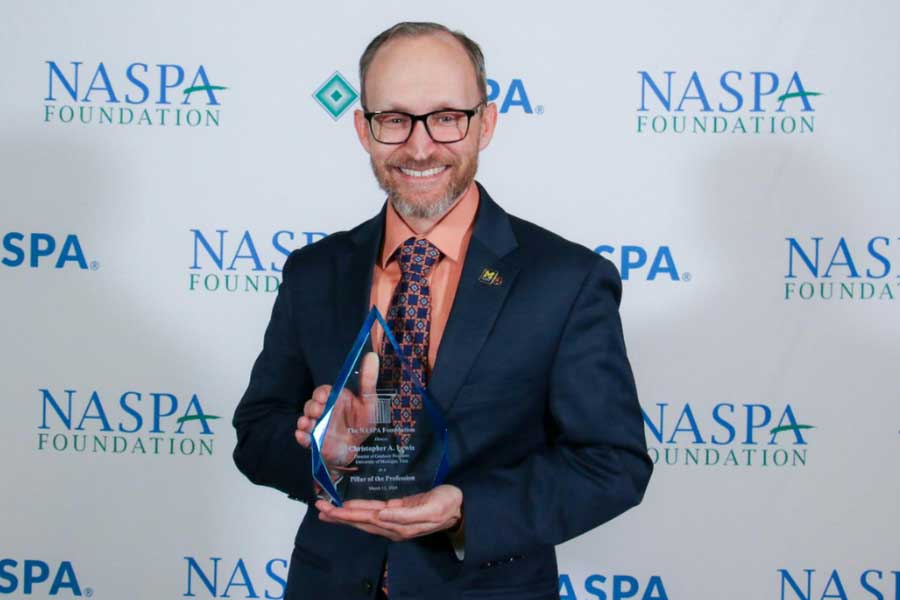 Christopher Lewis holding the NASPA Pillar of the Profession Award