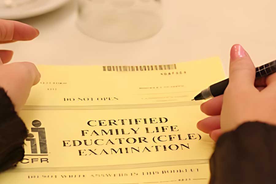student's hands resting on a copy of the Certified Family Life Education (CFLE) Examination